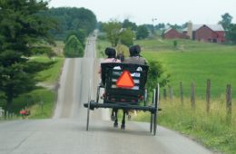 photo of two person riding on black carriage running on grey concrete road
