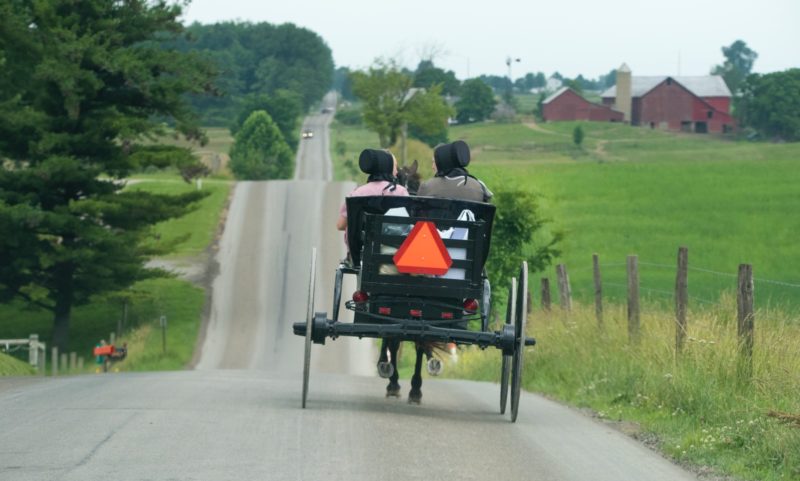 photo of two person riding on black carriage running on grey concrete road